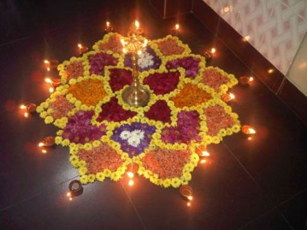 „Rangoli“ dizainas su gėlėmis ir degančiomis diyomis