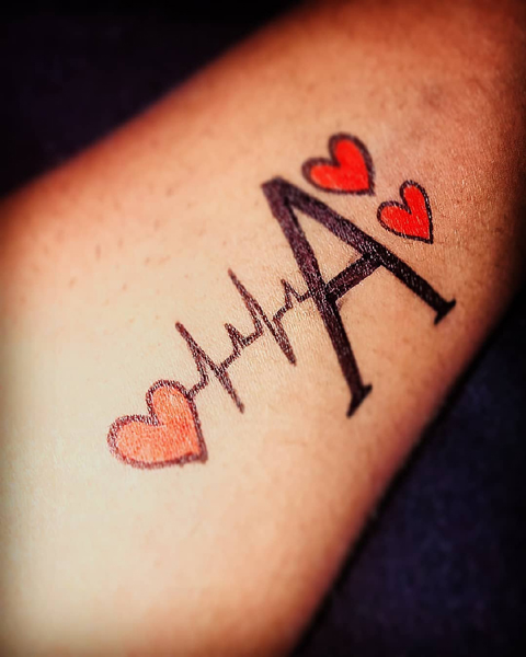Širdies plakimas su paryškinta raidės tatuiruote