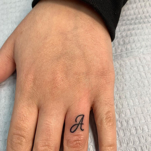 Raidės tatuiruotė ant žiedo piršto