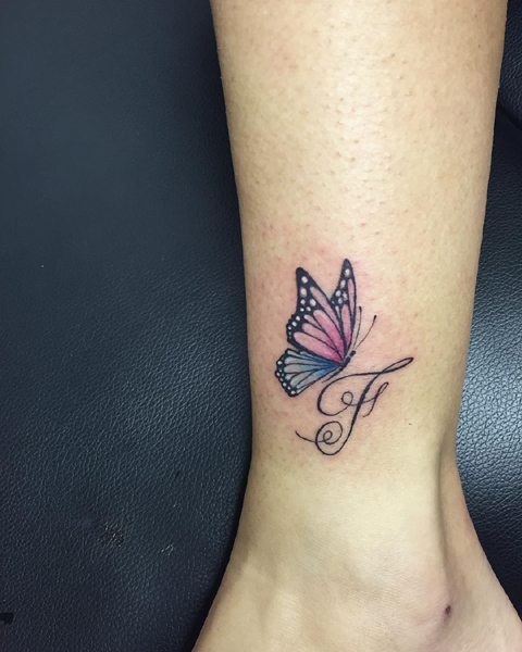Stilinga F raidės tatuiruotė su drugeliu