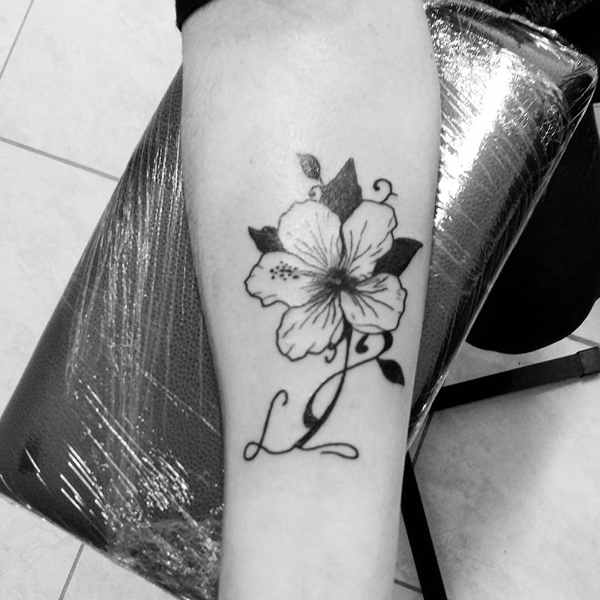 L raidės tatuiruotė su hibisko gėle