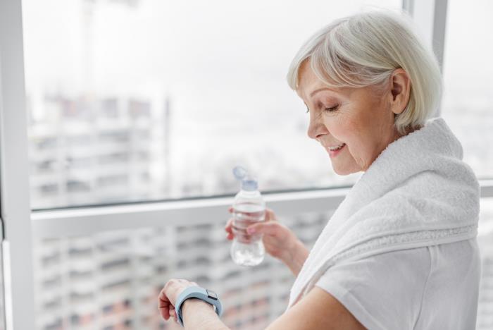 Απώλεια βάρους σε μεγάλη ηλικία Γυναίκα που πίνει άφθονο νερό ενώ ασκείται ενεργά, ελέγχει τον παλμό και την αρτηριακή πίεση