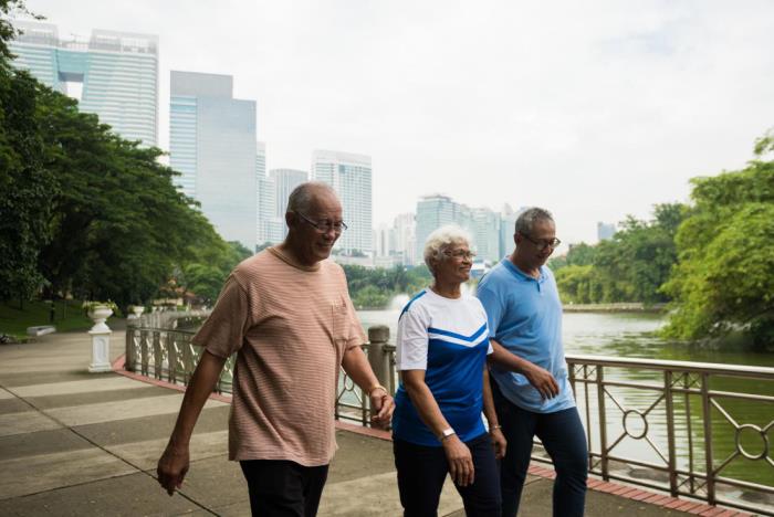 Τρεις ηλικιωμένοι φίλοι χάνουν βάρος περπατώντας δίπλα στο ποτάμι στο πάρκο σε μια μεγάλη πόλη