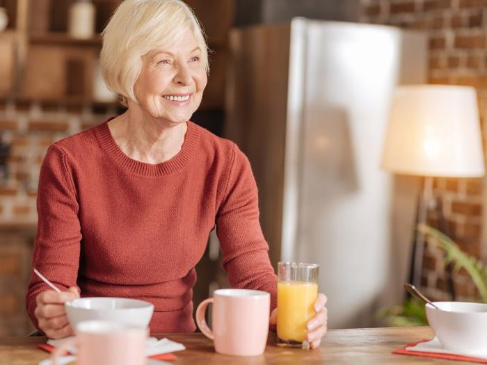 Η απώλεια βάρους ηλικιωμένη γυναίκα στην κουζίνα γράφει κάτι για ποτά smoothies τσάι