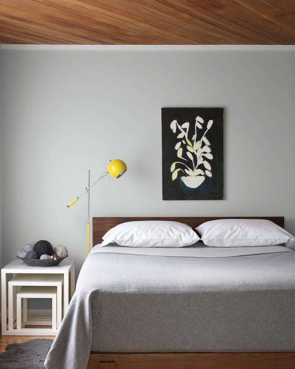 Τρέχοντα χρώματα τοίχου γκρι υπνοδωμάτιο ανοιχτό γκρι στον τοίχο κλινοσκεπάσματα λευκά μαξιλάρια μικρό φωτισμό σε κίτρινο φωτιστικό