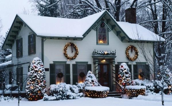 Βάλτε εξωτερικό φωτισμό για τα Χριστούγεννα - 30 εορταστικές ιδέες και συμβουλές λευκό σπίτι καλυμμένο με χιόνι με μικρά κίτρινα φώτα