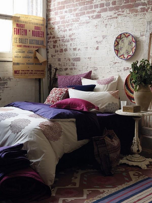 Τούβλο από τούβλα στο υπνοδωμάτιο με ρουστίκ πινελιές τόσο πολύχρωμο με διακοσμητικά μαξιλάρια και τόσο ελκυστικό