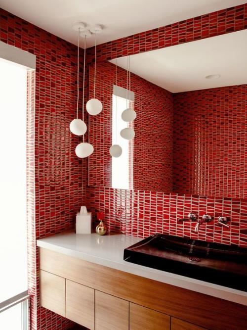Μπάνιο με κόκκινα, κόκκινα πλακάκια στους τοίχους, μεγάλους καθρέφτες τοίχου, λευκά κρεμαστά φώτα, λευκή ματαιοδοξία, μικρά αξεσουάρ μπάνιου