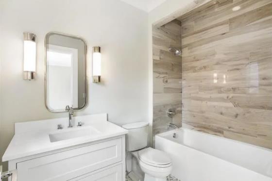 Τα πλακάκια του μπάνιου σε ξύλο δείχνουν Το ευρύχωρο μπάνιο WC White κυριαρχεί στον τοίχο της μπανιέρας με πλακάκια
