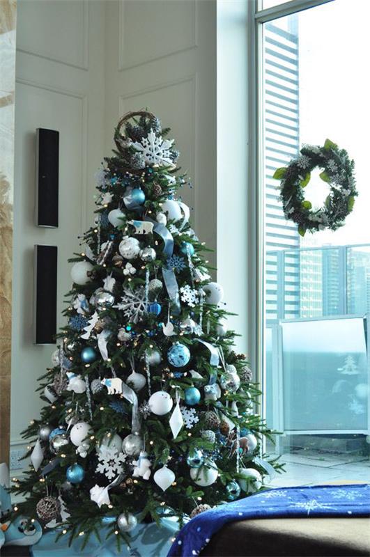 Μπλε και ασημί Χριστουγεννιάτικες γιορτές και παραμονή Πρωτοχρονιάς Χριστουγεννιάτικο δέντρο διακοσμημένο δίπλα στο στεφάνι του παραθύρου στο γυάλινο τζάμι