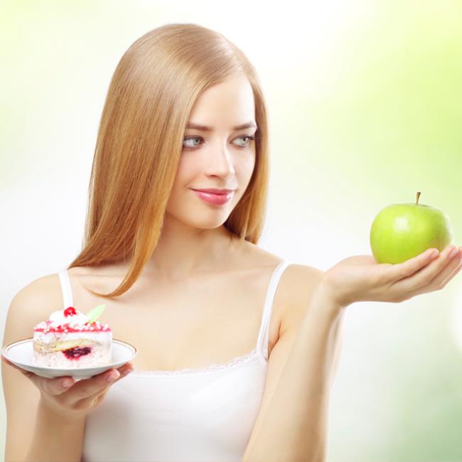 Κανόνες διατροφής το νεαρό κορίτσι με αμφιβολία τρώει μήλο ή περιποιείται τον εαυτό του με κάτι γλυκό