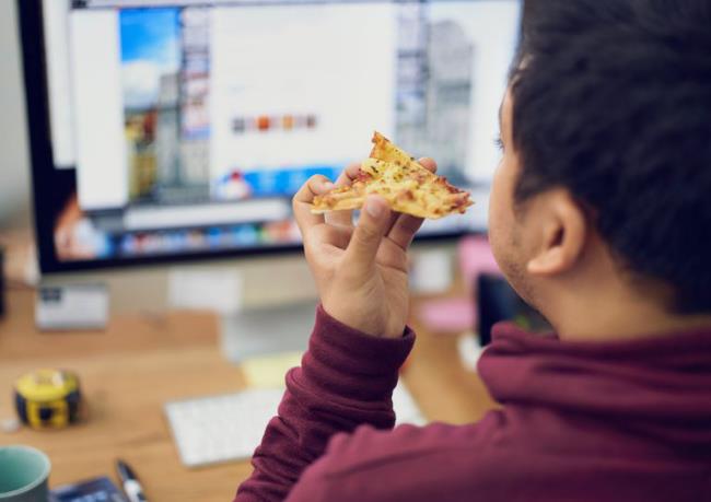 Οι παγίδες δίαιτας τρώνε πίτσα μπροστά από τον υπολογιστή στη δουλειά κακή συνήθεια στο γραφείο του σπιτιού