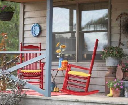 Απλή βεράντα με δύο κουνιστές καρέκλες κόκκινες για να ξεκουραστούν ανενόχλητοι
