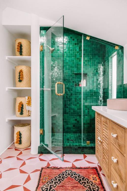 Οι πινελιές στο μπάνιο είναι δημιουργικές και τολμηρές για να διαχωρίσουν οπτικά τη γωνιά του ντους με σκούρα πράσινα πλακάκια και γυάλινο τοίχο