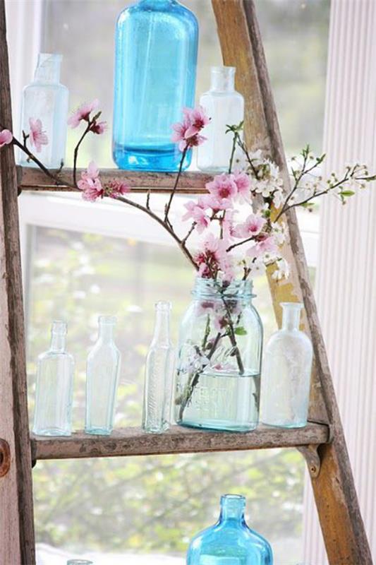Ανοιξιάτικη διακόσμηση με άνθη κερασιού τρία τρία κλαδιά ροζ ανθών στο ποτήρι στην παλιά ξύλινη σκάλα