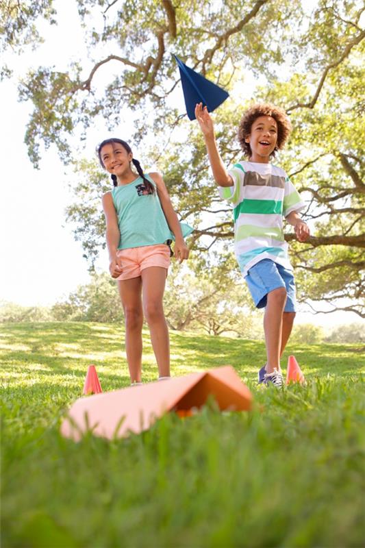 Υπαίθρια παιχνίδια στον κήπο για παιδιά που παίζουν χάρτινο αεροπλάνο