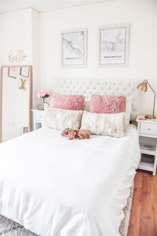 Λαμπερό υπνοδωμάτιο με ωραία κλινοσκεπάσματα σε λευκό ροζ διακοσμητικά μαξιλάρια αγκαλιά με λαμπτήρες παιχνιδιών εικόνες διακόσμηση τοίχου ανοιχτός καθρέφτης τοίχου