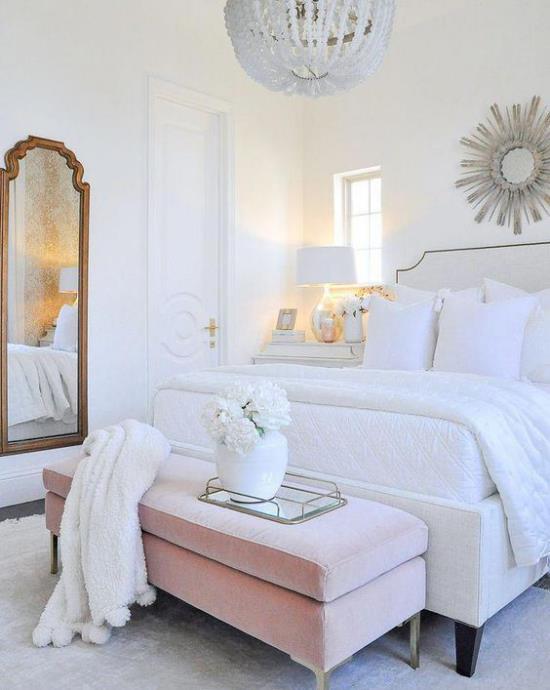 Λαμπερό υπνοδωμάτιο μεγάλο άνετο κρεβάτι λευκά κλινοσκεπάσματα ροζ πάγκο λευκό βάζο με λουλούδια καθρέφτη λευκό ρίξτε κουβέρτες