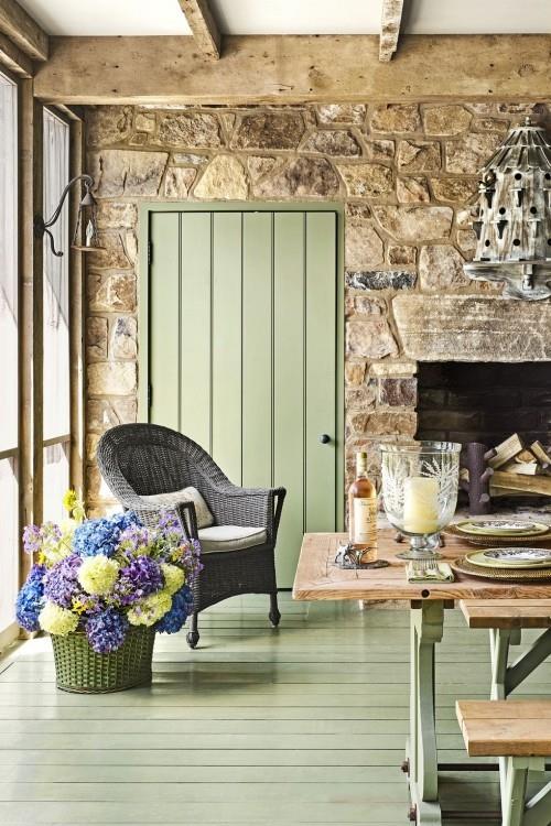 Ανοιχτό πράσινες βαμμένες σανίδες δαπέδου ρουστίκ πέτρινοι τοίχοι ξύλινα δοκάρια πολύ ελκυστικά λουλούδια δωματίου στο καλάθι