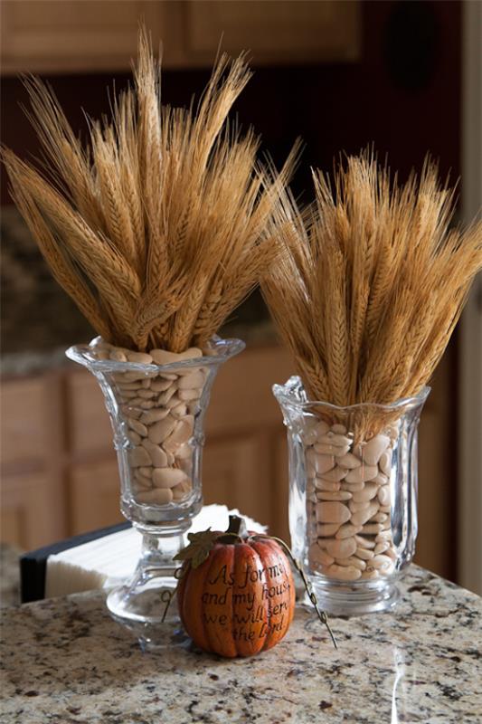 Φθινοπωρινή διακόσμηση με σιτάρι δύο ψηλά γυάλινα βάζα γεμάτα με φασόλια Κολοκύθα από κοτσάνια σίτου τοποθετημένα στο τραπέζι