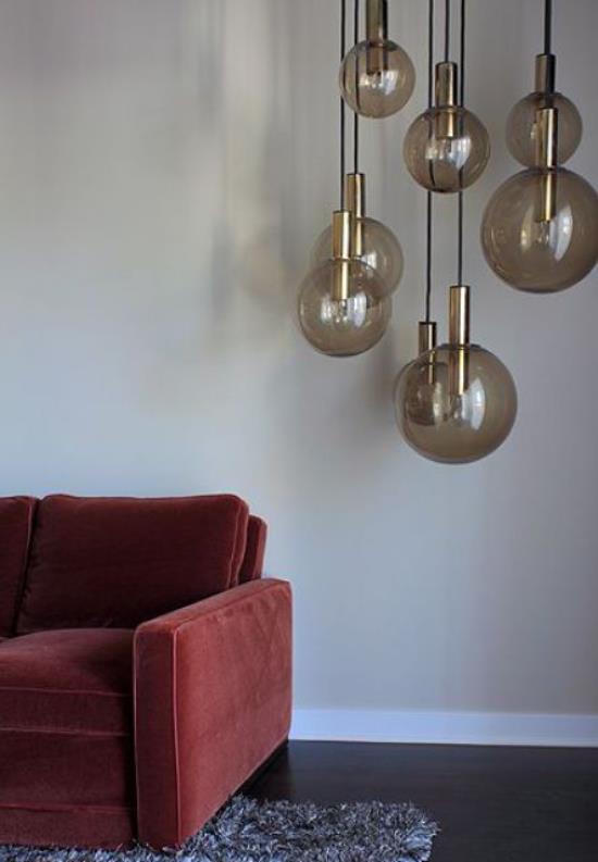 Κρεμαστά φώτα από γυαλί δίπλα στον καναπέ στο σαλόνι προσθέτουν γοητεία και άνεση