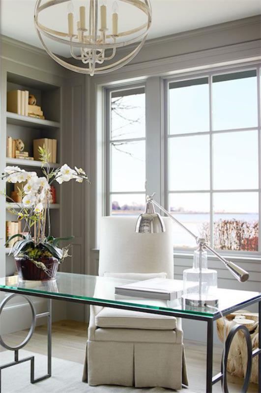 Γραφείο σπιτιού σε τραπέζι ουδέτερων χρωμάτων με γυάλινη κορυφή ορχιδέα κομψή λάμπα πολύ φως της ημέρας