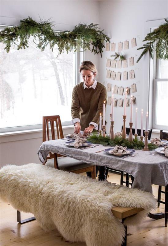 Η αίσθηση Hygge τα Χριστούγεννα έστρωσε το τραπέζι, κεριά, δέρμα προβάτου στον πάγκο, κλαδιά πεύκου δίπλα στο παράθυρο, απλή, ζεστή ατμόσφαιρα