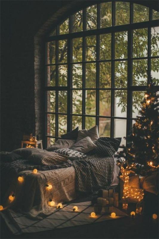 Αίσθηση Hygge τη Χριστουγεννιάτικη μαγική ατμόσφαιρα πολλά φώτα ύπνο κρεβάτι μεγάλο παράθυρο