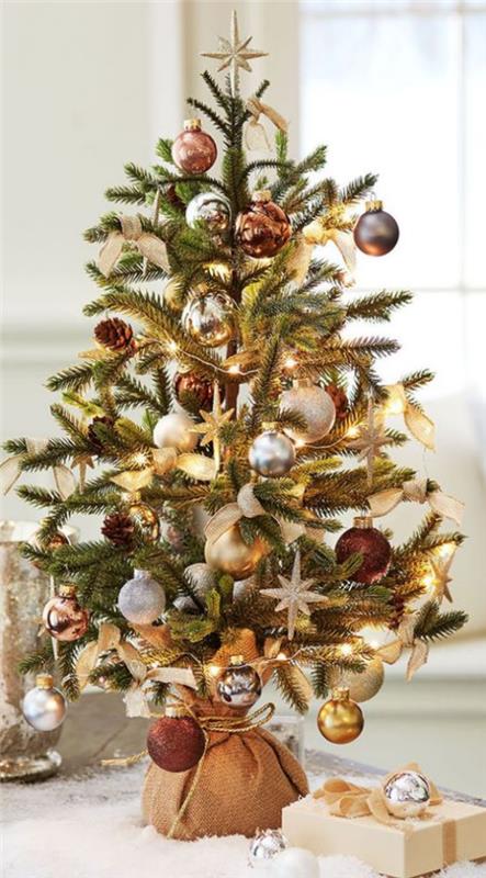 Μικρό χριστουγεννιάτικο δέντρο διακοσμεί βιτρίνα σκούρα κόκκινα ασημένια και χρυσά μπαλάκια σε σάκο λινάτσα