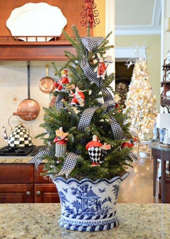 Μικρή διακόσμηση χριστουγεννιάτικου δέντρου που εκτίθεται σε ένα όμορφο μπλε και άσπρο δοχείο με φιόγκο στον πάγκο της κουζίνας