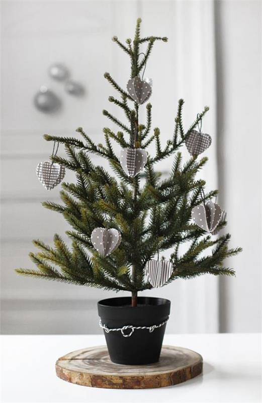 Διακοσμήστε ένα μικρό χριστουγεννιάτικο δέντρο, βάλτε μικρά κοσμήματα στο μαύρο δοχείο σε έναν ξύλινο δίσκο