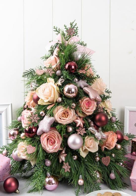 Μικρό χριστουγεννιάτικο δέντρο στολίζει καμαρώνει διακοσμημένο με μπιχλιμπίδια και τριαντάφυλλα για να τραβήξει τα βλέμματα