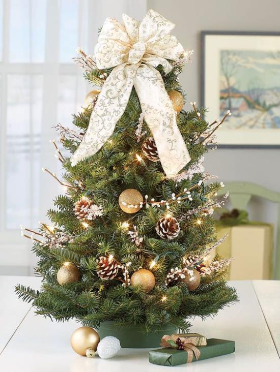 Διακοσμήστε το μικρό χριστουγεννιάτικο δέντρο που εκτίθεται με κουκουνάρια μεγάλες φιόγκους χρυσές μπάλες