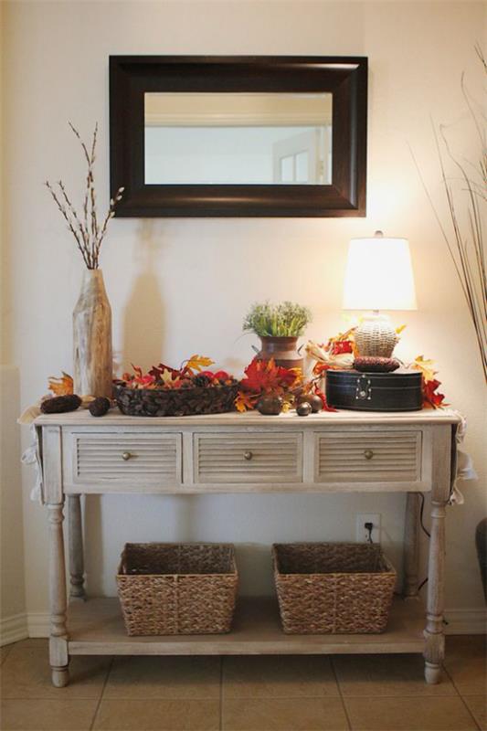 Το τραπέζι της κονσόλας διακοσμεί το φθινόπωρο ζεστά χρώματα λάμπα καλό φωτισμό πολύχρωμα φθινοπωρινά φύλλα ψάθινα καλάθια καθρέφτη τοίχου
