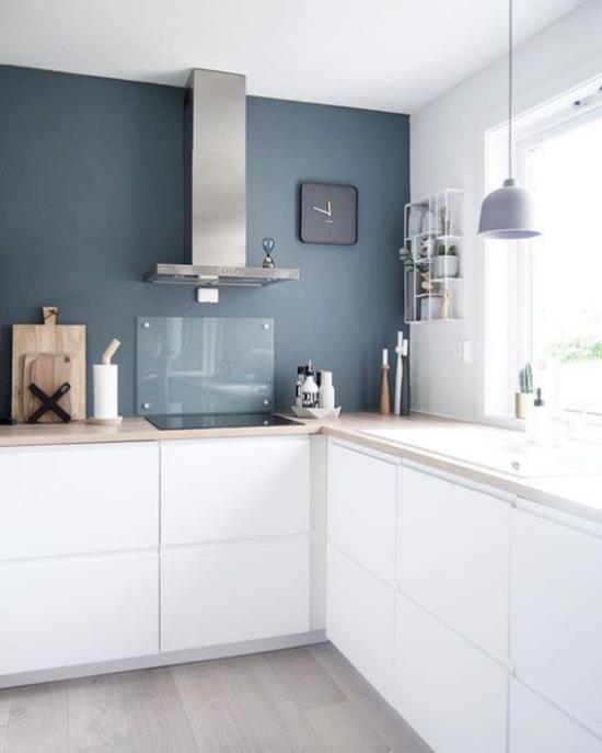 Μονάδες λευκής βάσης L-κουζίνας σε σκούρο μπλε τοίχο σε αντίθεση χρώματος απορροφητήρα