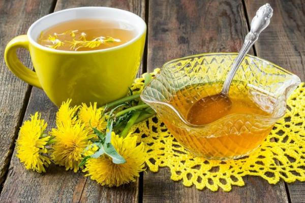 Πικραλίδα κίτρινα λουλούδια αφήνει φλιτζάνι τσάι πικραλίδα μικρό μπολ με μέλι δίπλα του