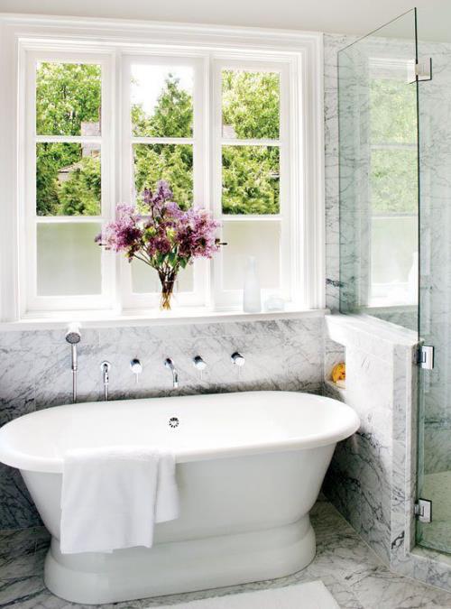 Μάρμαρο στο μπάνιο μαρμάρινα πλακάκια λευκή μπανιέρα μπροστά από το βάζο του παραθύρου με λουλούδια γυναικεία αίσθηση