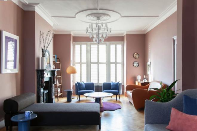 Μοντέρνο σαλόνι σαλόνι ροζ τοίχοι άνετα έπιπλα πέτρινο τζάκι μοβ χαλί