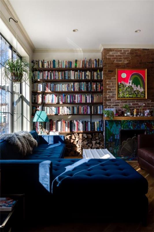 Σύγχρονη βιβλιοθήκη σπιτιού ένας τοίχος με βιβλία δίπλα στο τζάκι άνετος καναπές σε μπλε φως