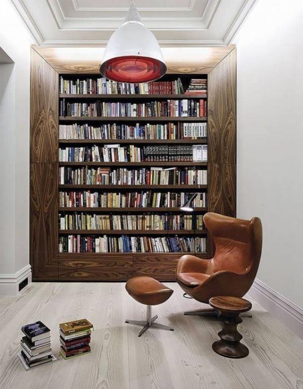 Σύγχρονη βιβλιοθήκη σπιτιού, κλασικός σχεδιασμός τοίχου βιβλίων, δερμάτινη πολυθρόνα μπροστά