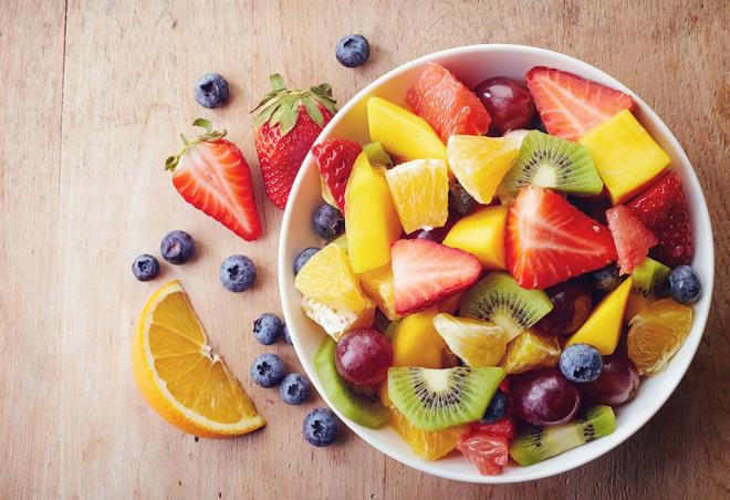 Φάτε υγιή φρούτα απώλεια βάρους πλούσια φρουτοσαλάτα πορτοκάλια ακτινίδιο φράουλες βατόμουρα κομμένα σε κομμάτια σε ένα μπολ.