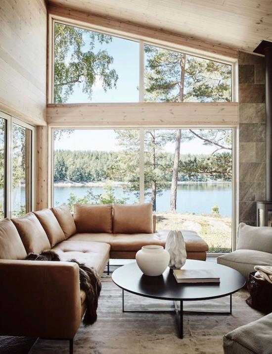 Έξυπνη χρήση του χώρου στο γωνιακό παράθυρο ανοιχτό καφέ δερμάτινο καναπέ μικρή στρογγυλή πολυθρόνα τραπεζάκι σαλονιού υπέροχη θέα