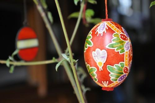 Κόκκινα Πασχαλινά αυγά που ζωγραφίζουν κρεμαστά λουλούδια σε ένα δέντρο