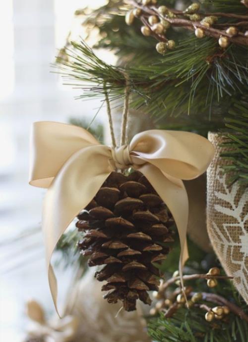 Οι ρουστίκ χριστουγεννιάτικες διακοσμήσεις κάνουν κουκουνάρια με ένα φιόγκο σε κρεμ χρώμα για το χριστουγεννιάτικο δέντρο