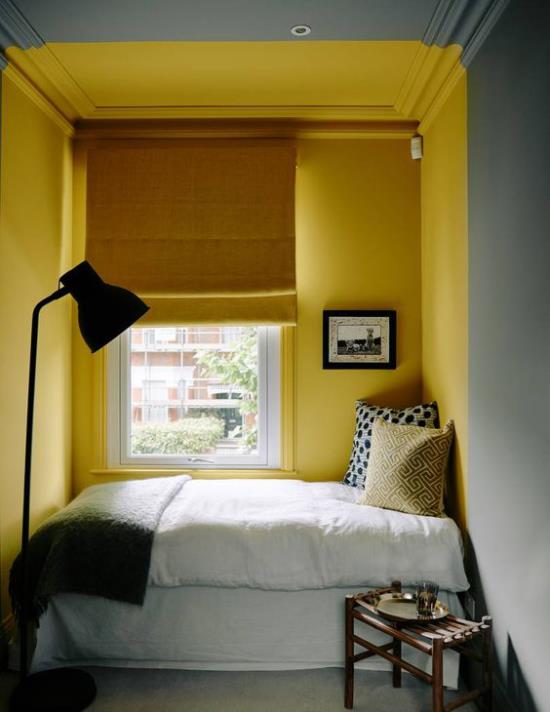 Ιδέες κρεβατοκάμαρας σε γκρι και κίτρινο μικρό δωμάτιο κρεβάτι μπροστά από το παράθυρο κίτρινο τοίχο κίτρινες περσίδες λευκά κλινοσκεπάσματα