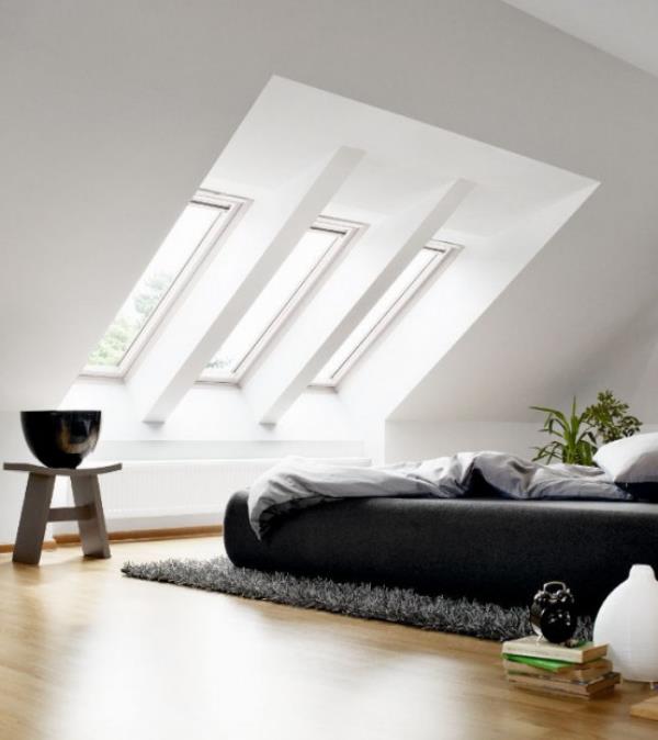 Μινιμαλιστικό υπνοδωμάτιο με κομψό εσωτερικό σχεδιασμό στη σοφίτα κάτω από κεκλιμένο κρεβάτι φεγγίτη οροφής με κεκλιμένη οροφή