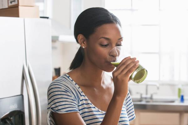 Νεαρή γυναίκα από χυμό σέλινου Πίνοντας πράσινη εμποτισμένη υγιεινή φυσική θαυματουργή θεραπεία
