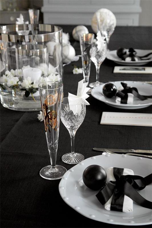 Γιορτάστε την παραμονή της Πρωτοχρονιάς στο σπίτι μαύρο προτιμώμενο χρώμα διακοσμητικό τραπεζομάντηλο λευκά ποτήρια πορσελάνης από κρύσταλλο