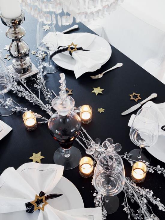 Γιορτάζοντας την παραμονή της Πρωτοχρονιάς στο σπίτι ένα εορταστικό τραπέζι μαύρο τραπεζομάντηλο λευκή εξυπηρέτηση λευκές χαρτοπετσέτες όμορφη αντίθεση