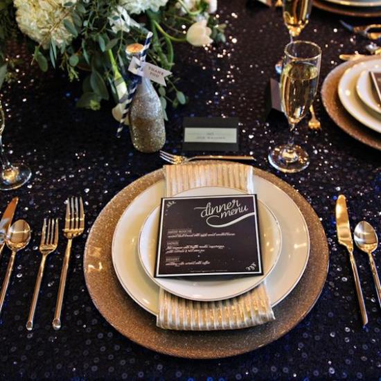 Γιορτάζοντας την παραμονή της Πρωτοχρονιάς στο τραπέζι του σπιτιού στρίβοντας μαύρο τραπεζομάντηλο χρυσό λάμψη ωραία μαχαιροπίρουνα επίσης σε χρυσό